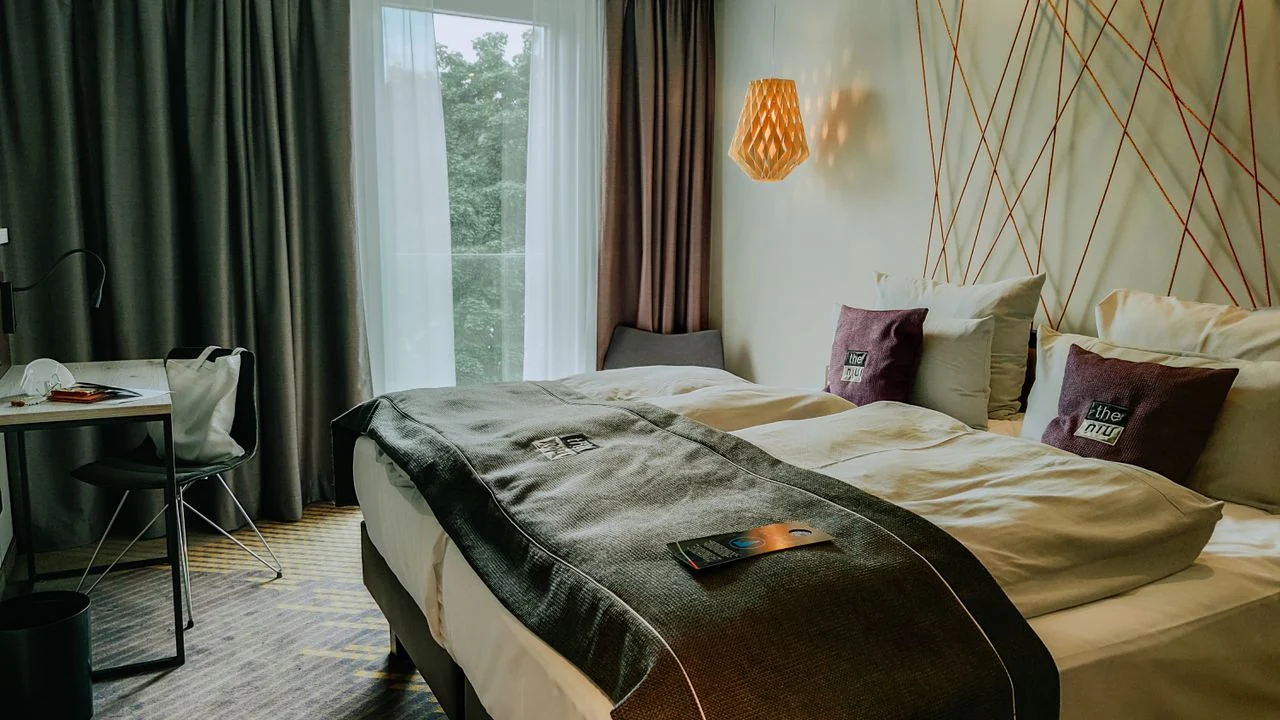 Hotel bedroom with a double bed, curtains, a window and a small table