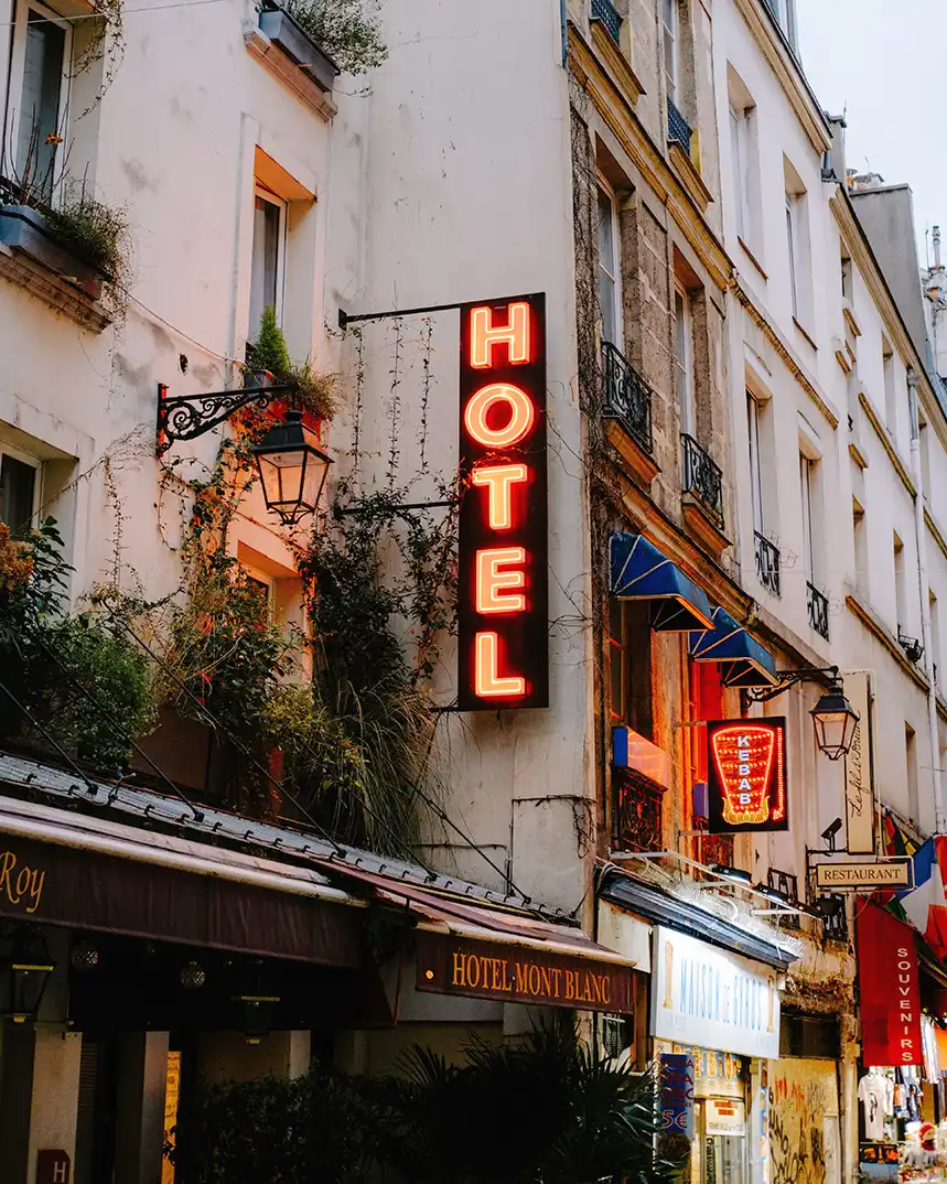 Orange hotel sign on a historic city building with balconies and trailing greenery