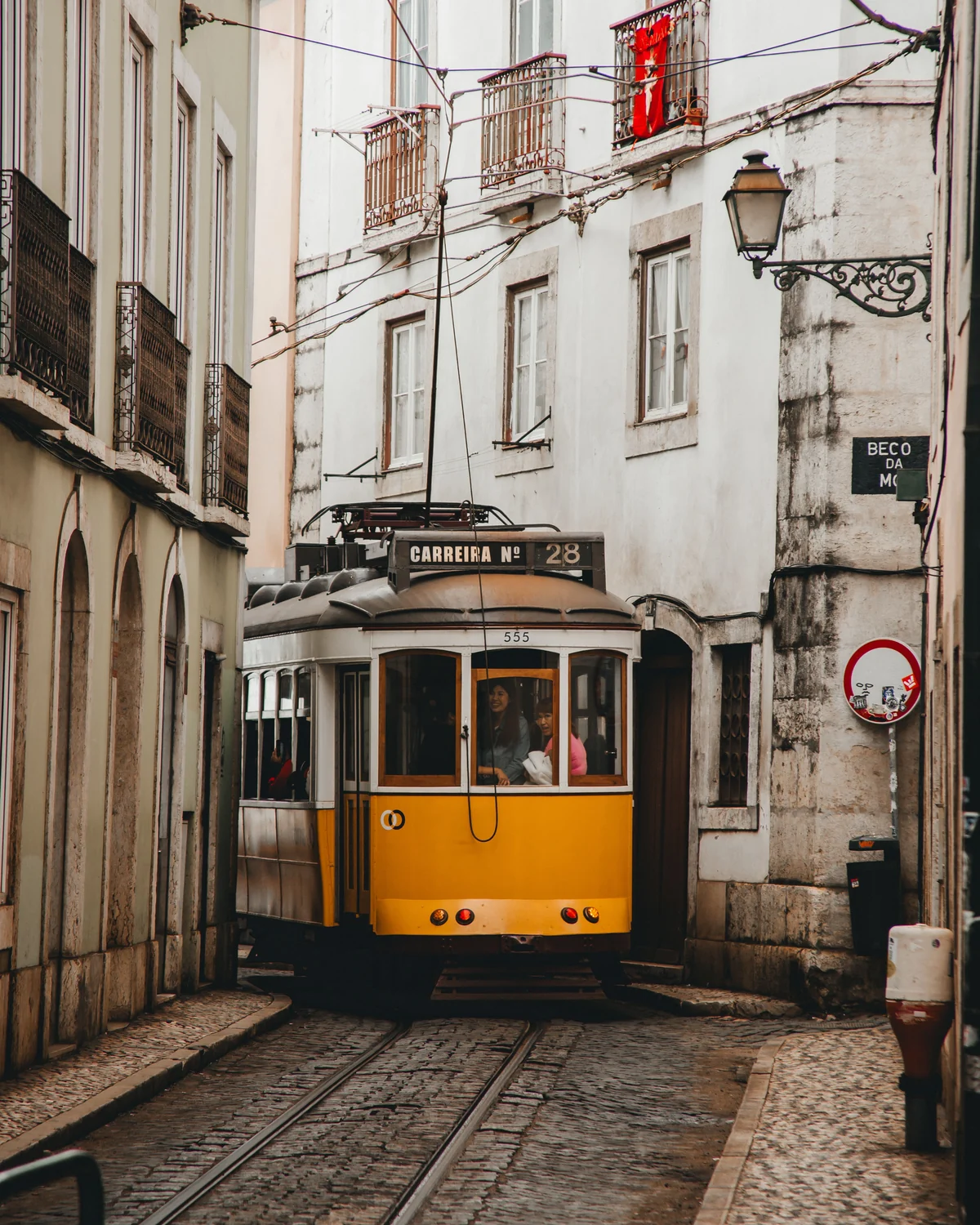 Yellow tram on a narrow Lisbon street lined with historic buildings