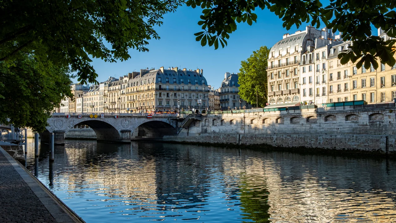 Paris riverside buildings and a stone bridge reflected in the Seine