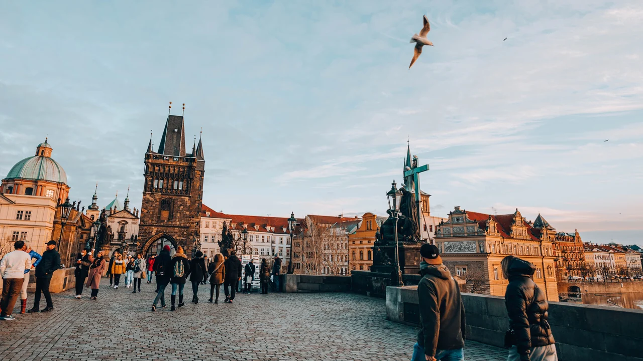 People walking across Prague’s Charles Bridge towards the Old Town Bridge Tower