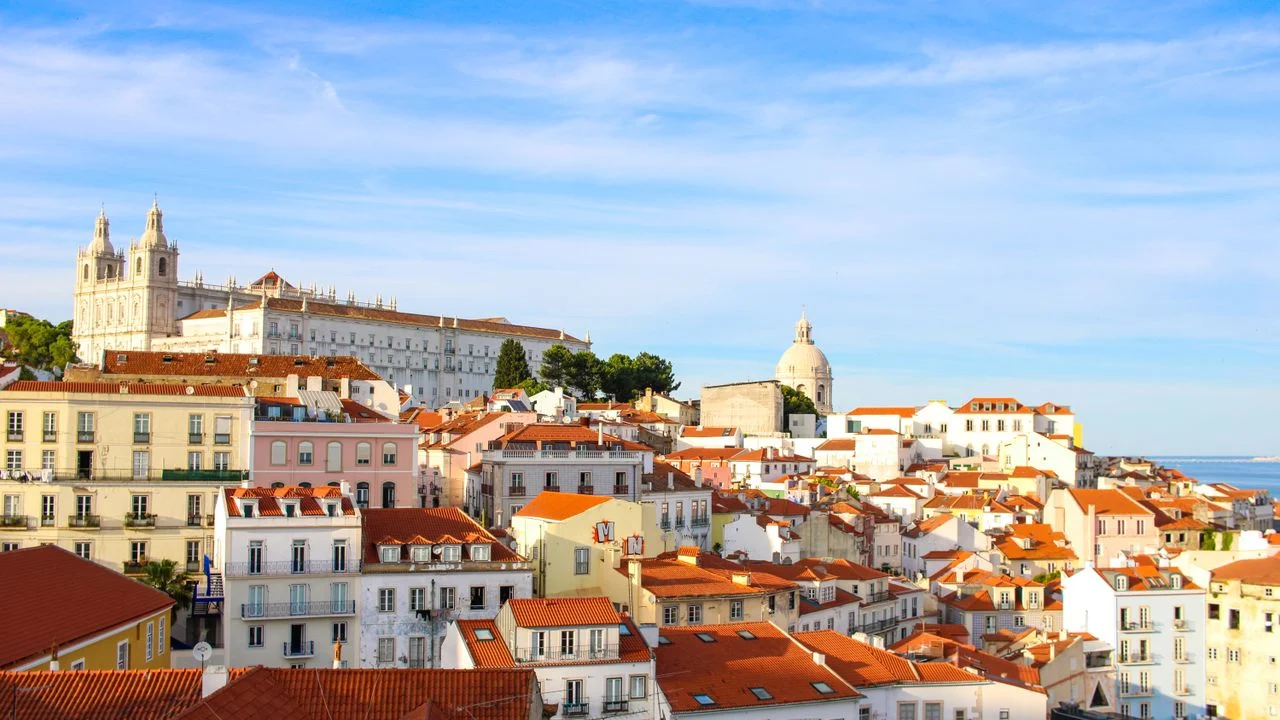 Terracotta rooftops of Alfama with churches above Lisbon