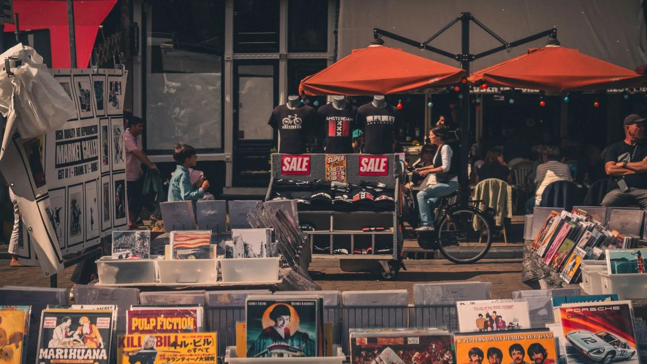 Records displayed at an Amsterdam street market beside café tables