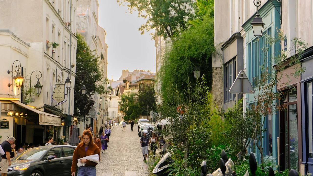 A curved street with café tables and trees in Montmartre, Paris