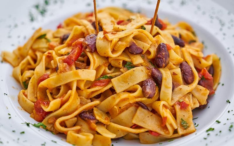 a plate of pasta with red beans and tomatoes