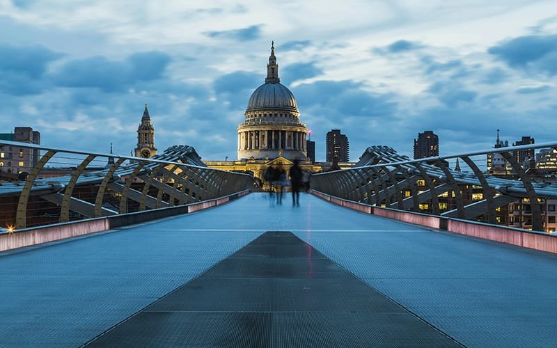 Millennium Bridge, London with a dome and a building in the background