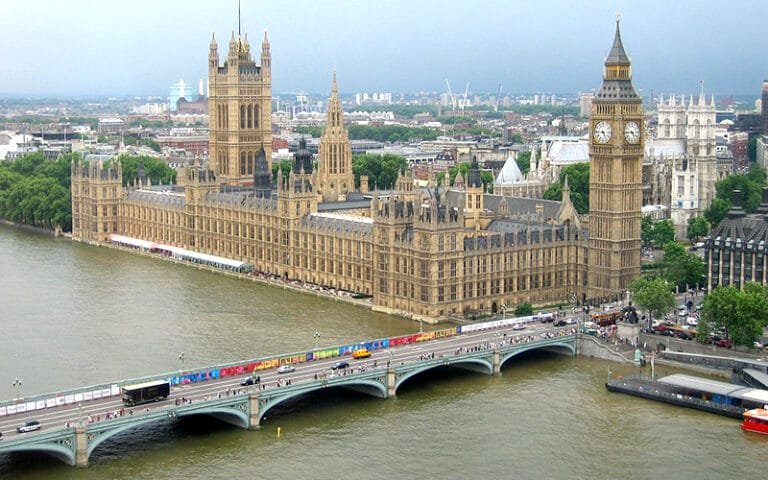 a large building with a clock tower and a bridge over a river