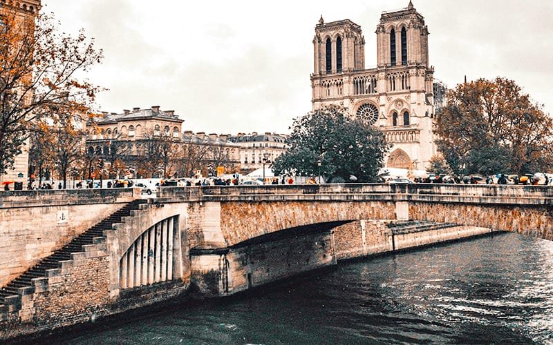 a bridge over a river with a large building in the background