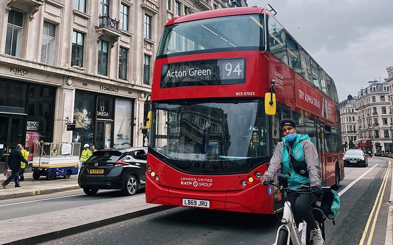 a person on a bicycle next to a double decker bus