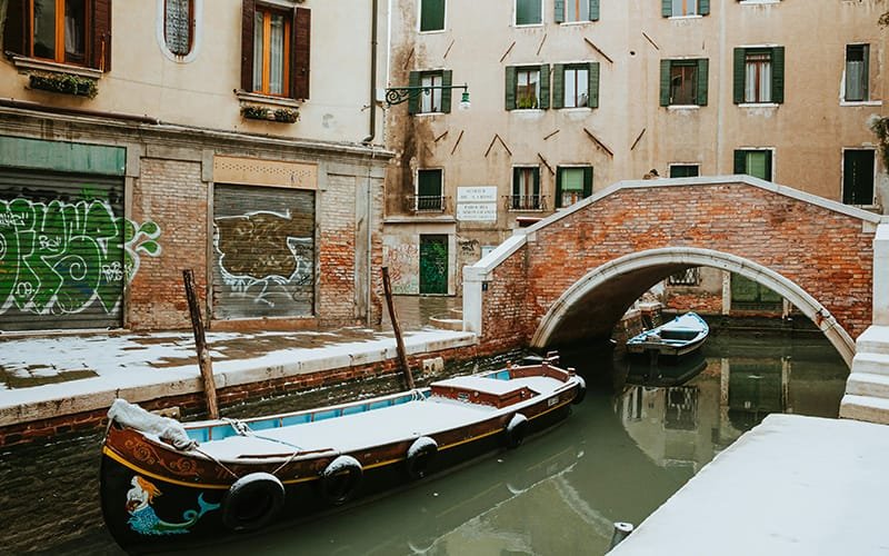 boats in a canal with a bridge and buildings