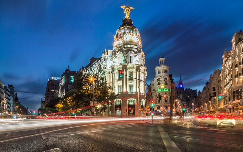 a street with cars and a building with a statue on top