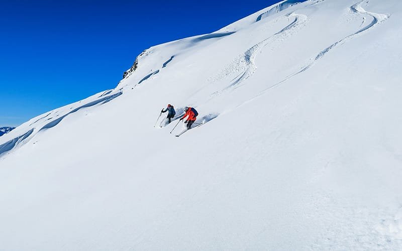 a group of people skiing down a snowy mountain