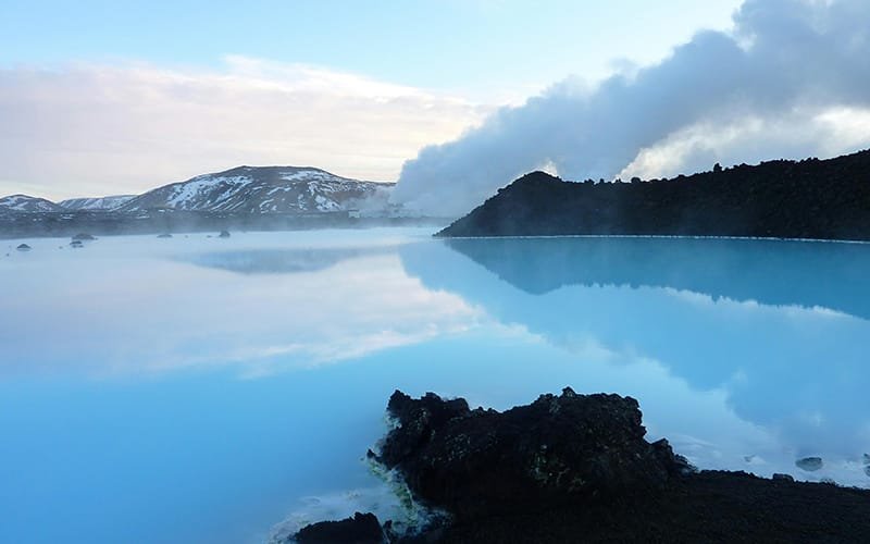 a blue lake with a mountain in the background