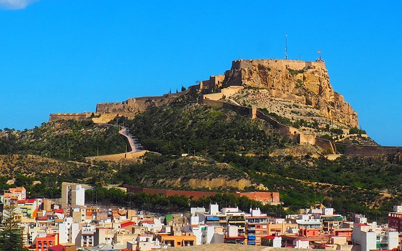 a large stone castle on a hill with a city in the background